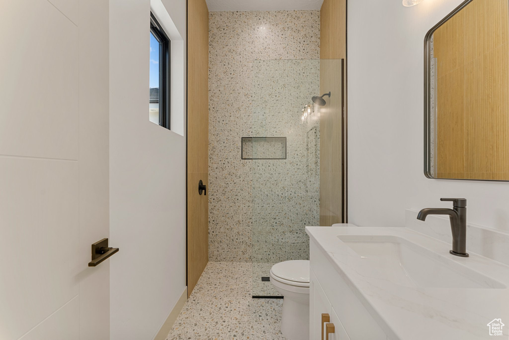 Bathroom with vanity, tiled shower, and toilet