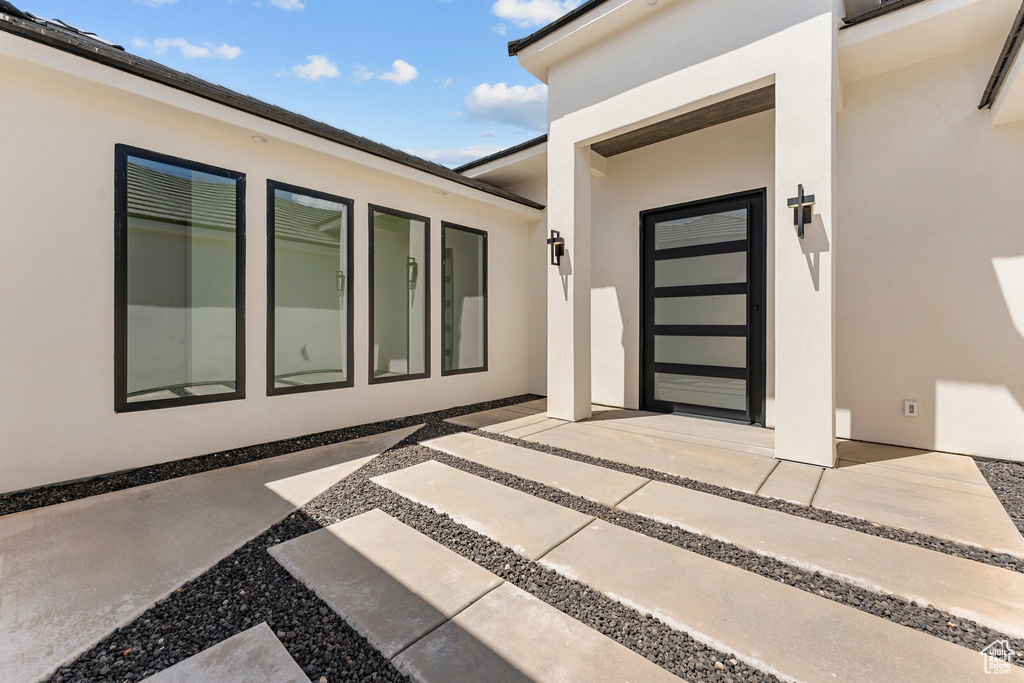 Doorway to property featuring stucco siding and a patio area