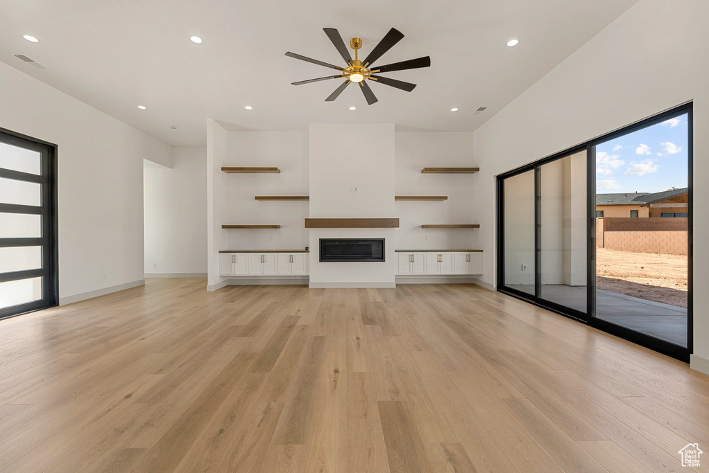 Unfurnished living room with ceiling fan, light wood-type flooring, a glass covered fireplace, recessed lighting, and baseboards