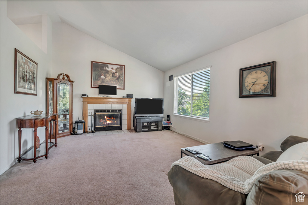 Living room featuring light colored carpet, lofted ceiling, and a tiled fireplace