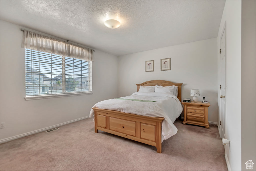 Bedroom with light colored carpet and a textured ceiling
