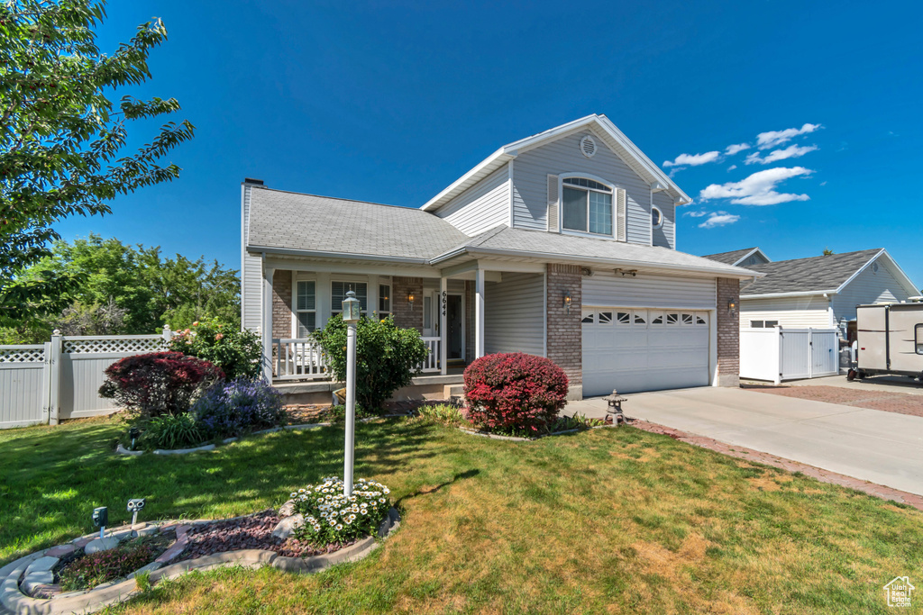 Traditional home with an attached garage, driveway, a porch, a gate, and brick siding