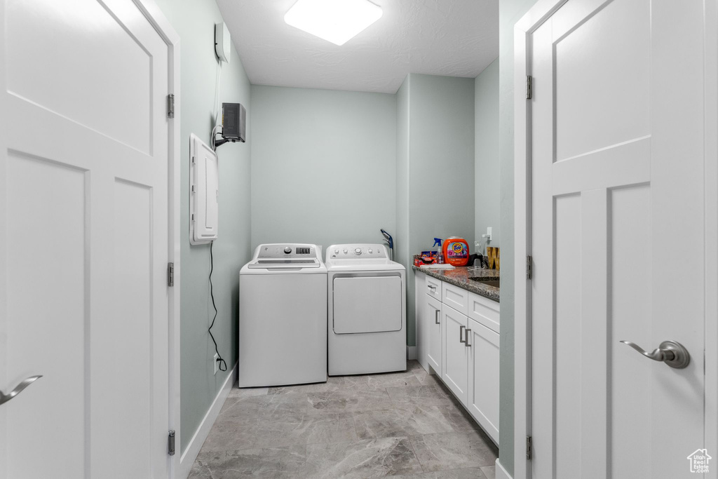 Washroom with cabinet space, separate washer and dryer, electric panel, and a textured ceiling