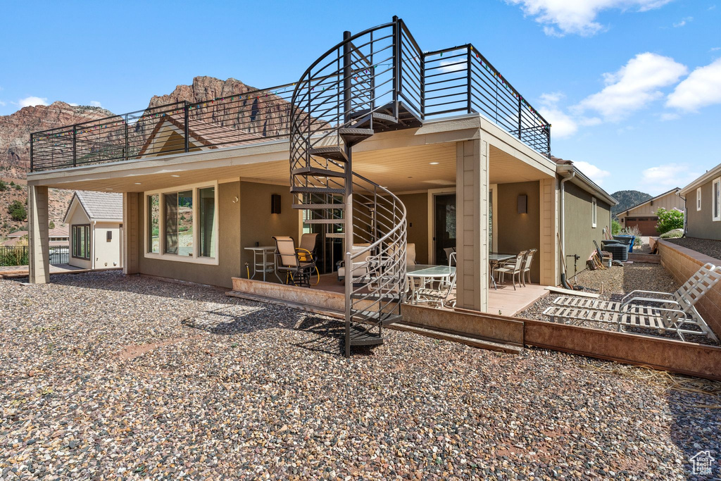Rear view of property featuring a patio, stairs, and stucco siding