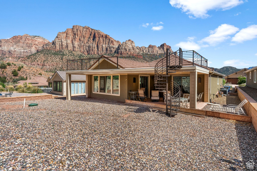 Rear view of house with a mountain view, a patio area, stairway, and stucco siding