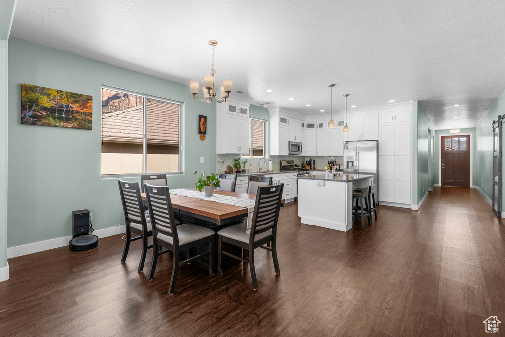 Dining space with a chandelier, dark wood finished floors, and recessed lighting