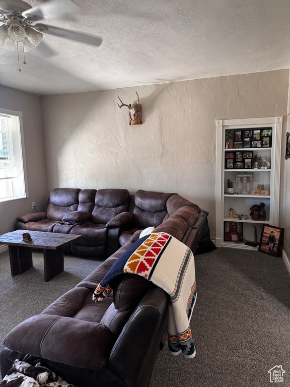 Carpeted living room with a textured ceiling, a ceiling fan, and a textured wall