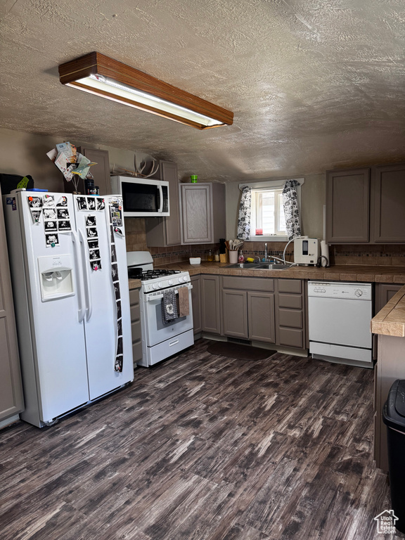 Kitchen with white appliances, a textured ceiling, dark wood-style flooring, and gray cabinets