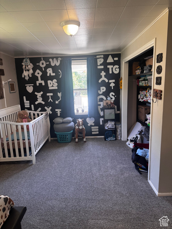Bedroom featuring carpet, ornamental molding, and a crib