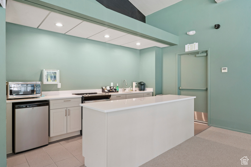 Kitchen featuring appliances with stainless steel finishes, white cabinetry, light countertops, a kitchen island, and recessed lighting