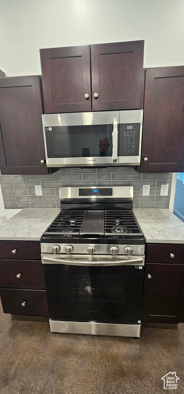 Kitchen featuring stainless steel appliances, light countertops, decorative backsplash, and dark brown cabinets