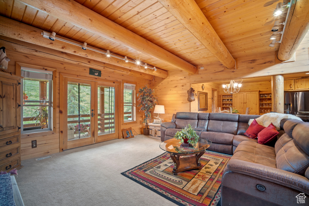 Living area with rail lighting, a chandelier, carpet flooring, wood walls, and a wood ceiling with exposed beams