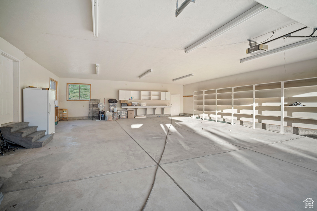 Garage featuring freestanding refrigerator and a garage door opener