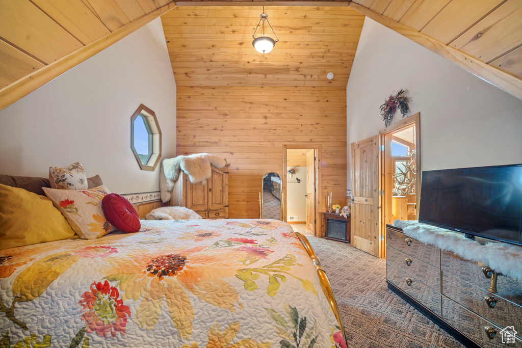 Carpeted bedroom featuring wood ceiling, wooden walls, and high vaulted ceiling