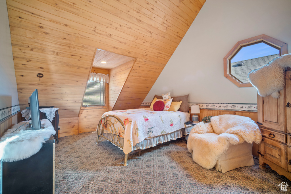 Carpeted bedroom with wood walls, wooden ceiling, a wainscoted wall, and vaulted ceiling