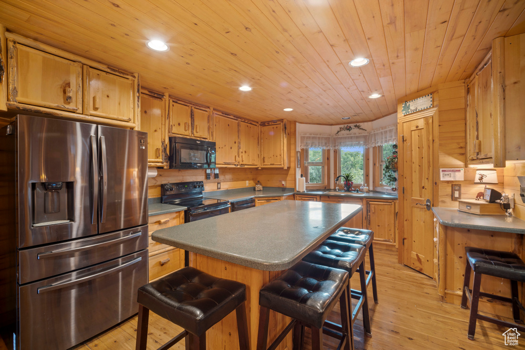 Kitchen with black appliances, a breakfast bar area, recessed lighting, light wood finished floors, and wooden ceiling