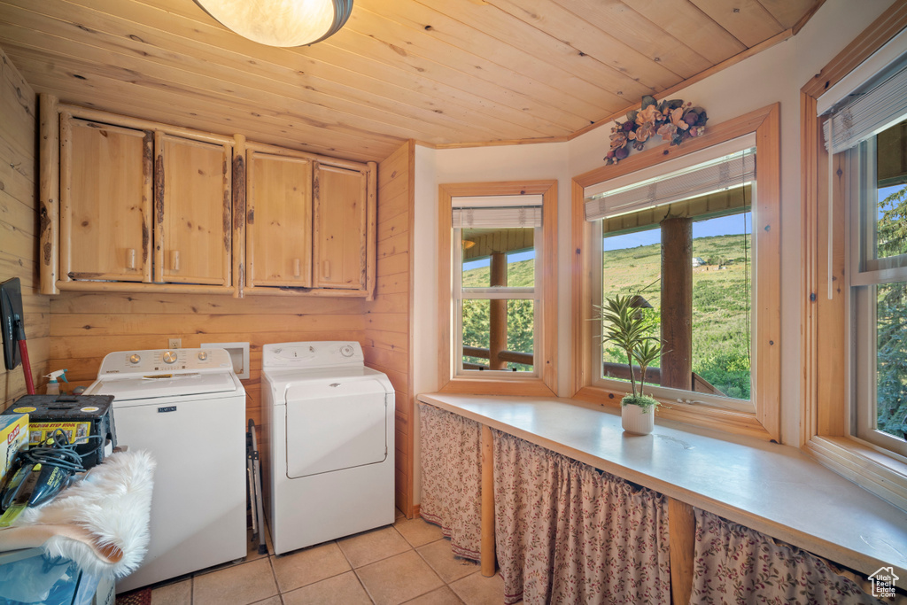 Laundry area with cabinet space, separate washer and dryer, light tile patterned floors, wood ceiling, and plenty of natural light