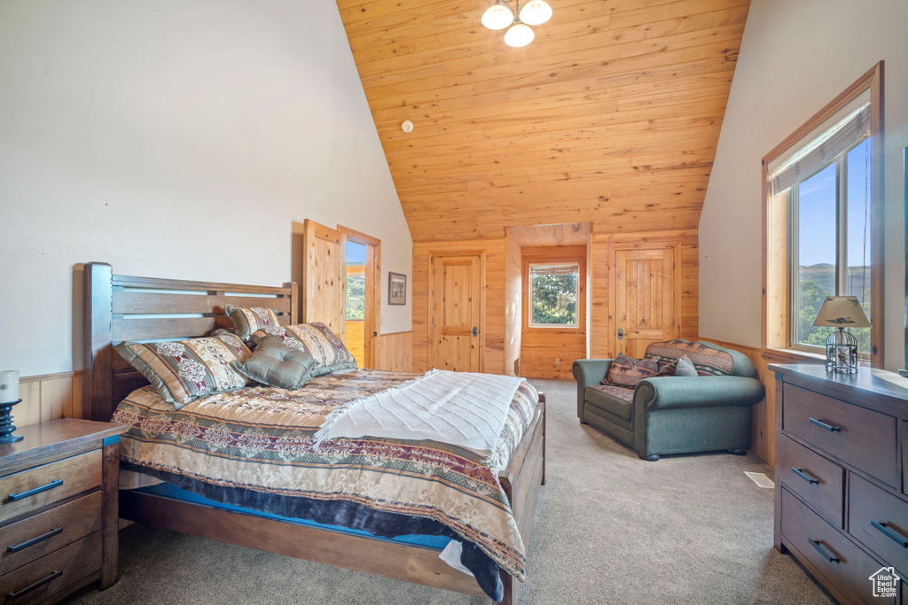 Carpeted bedroom with wood walls, wood ceiling, wainscoting, and high vaulted ceiling