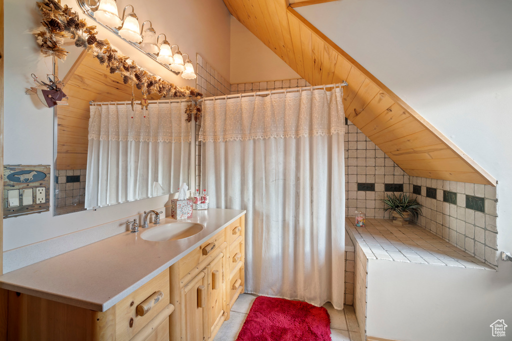 Bathroom featuring vaulted ceiling, vanity, and tile patterned flooring