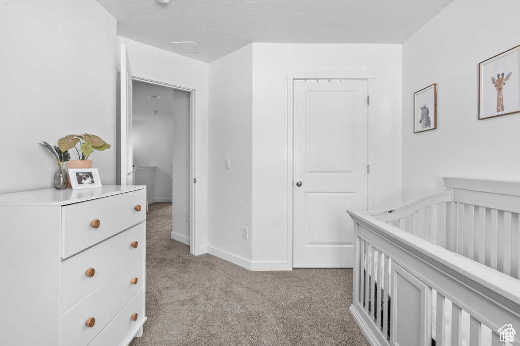 Bedroom featuring light carpet and a nursery area