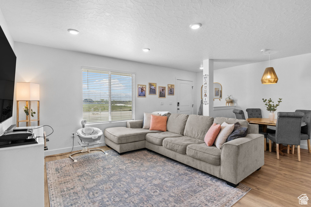 Living room with light wood-type flooring, a textured ceiling, and recessed lighting