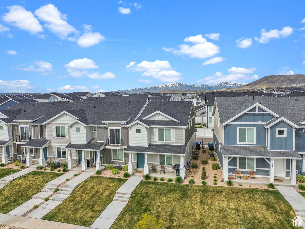 View of property featuring a residential view, a porch, a mountain view, roof with shingles, and a front yard