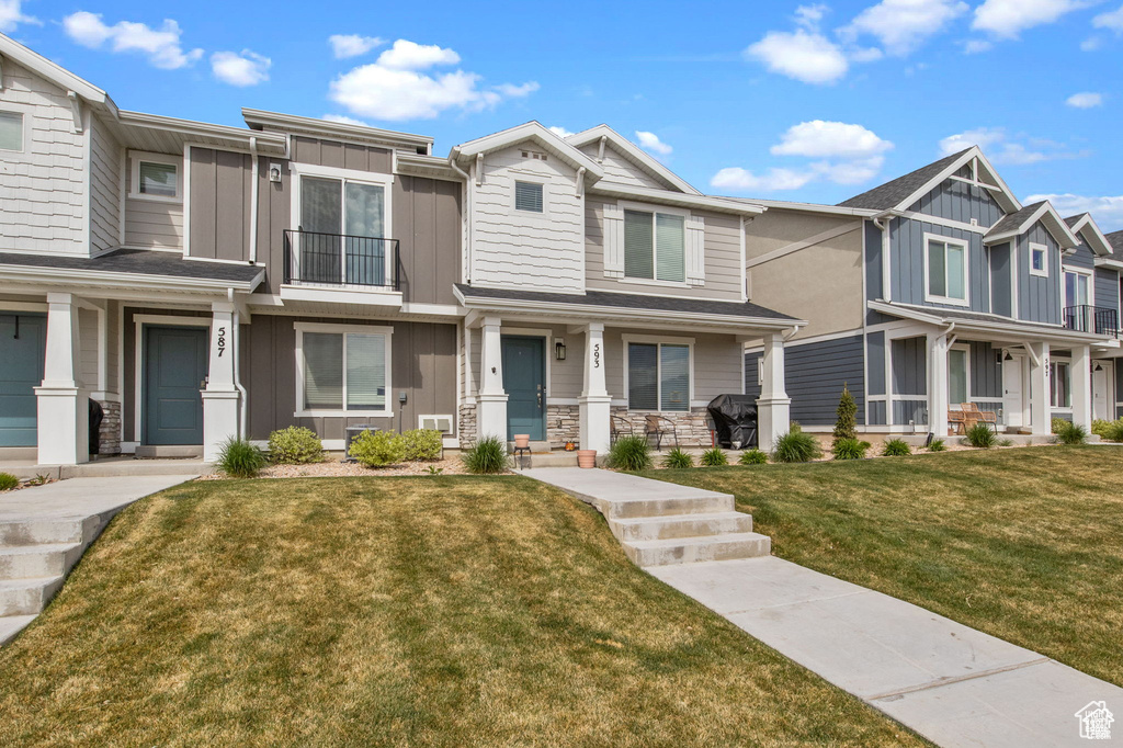 View of front of property featuring board and batten siding, a residential view, a front lawn, and stone siding