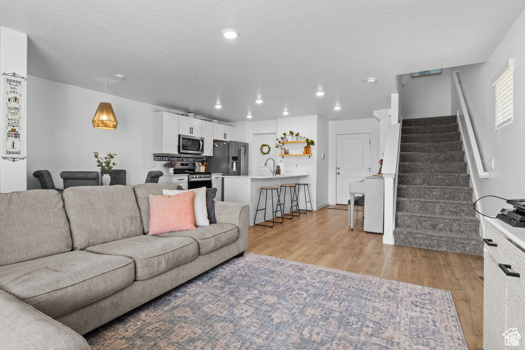Living room featuring light wood finished floors, stairs, recessed lighting, and a textured ceiling
