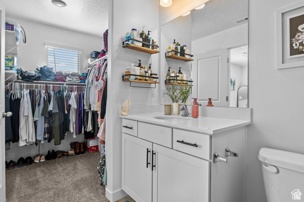 Bathroom featuring vanity, a textured ceiling, and a spacious closet