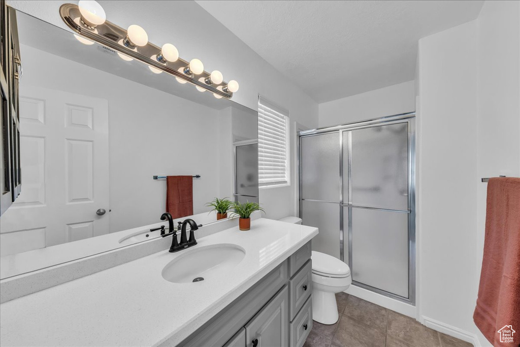 Full bath with vanity, a stall shower, and tile patterned floors