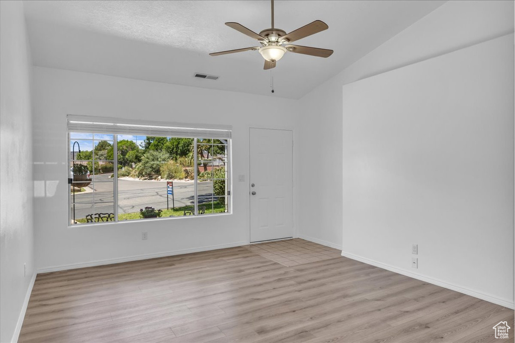 Empty room featuring wood finished floors, a ceiling fan, and lofted ceiling
