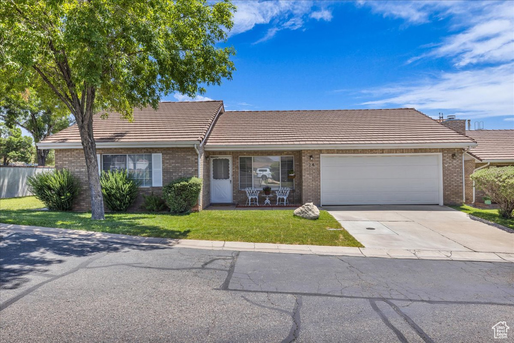 Ranch-style house with a tiled roof, an attached garage, and brick siding