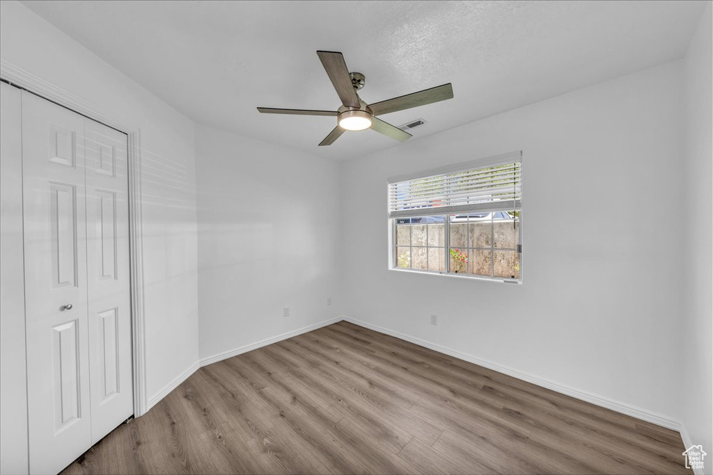 Unfurnished bedroom with wood finished floors, a closet, and a ceiling fan