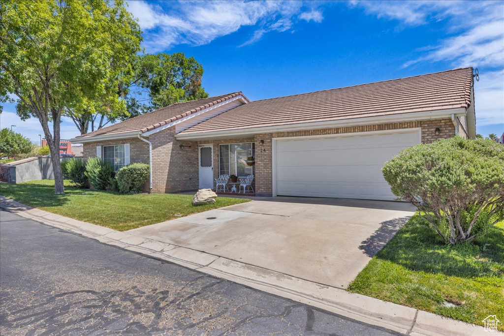 Single story home with a tile roof, brick siding, and an attached garage