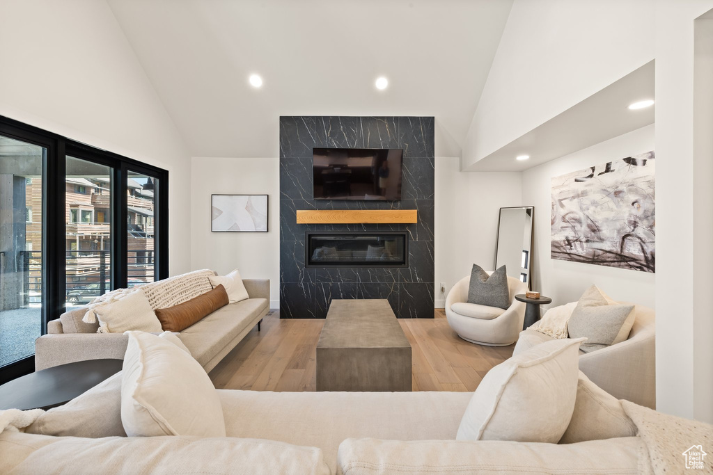 Living room with high vaulted ceiling, recessed lighting, a fireplace, and wood finished floors