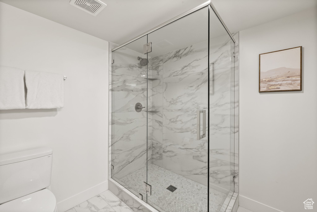Full bath featuring marble look tile flooring and a marble finish shower