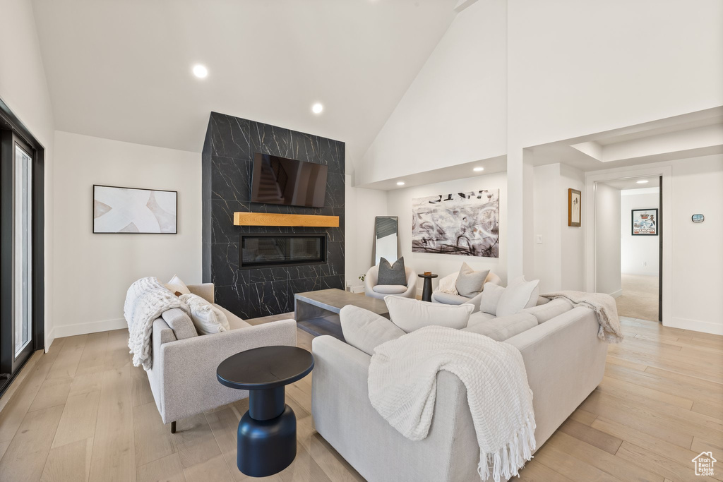Living area featuring a high end fireplace, high vaulted ceiling, light wood finished floors, and recessed lighting