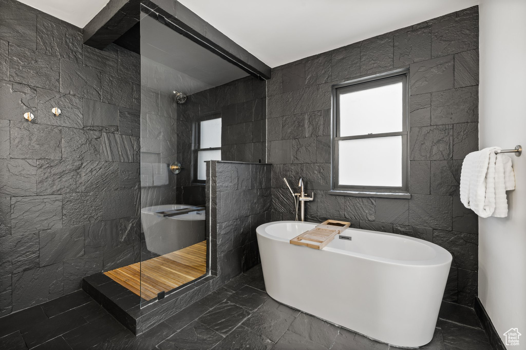 Full bathroom featuring a walk in shower, tile walls, a freestanding bath, and marble finish flooring