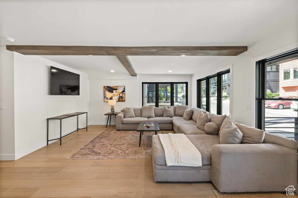 Living room with beam ceiling, light wood-type flooring, and recessed lighting