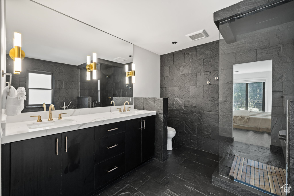 Full bathroom with tile walls, marble tiled flooring, ensuite bathroom, and double vanity