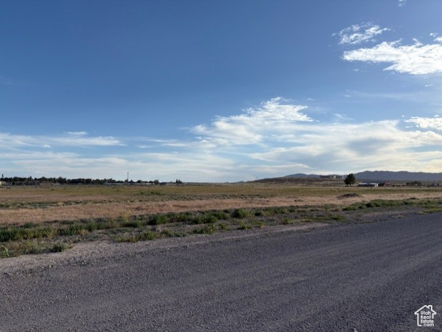 View of asphalt street featuring a view of rural / pastoral area and a mountain view