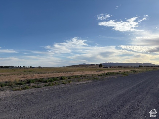 View of asphalt road with a view of rural / pastoral area and a mountain view