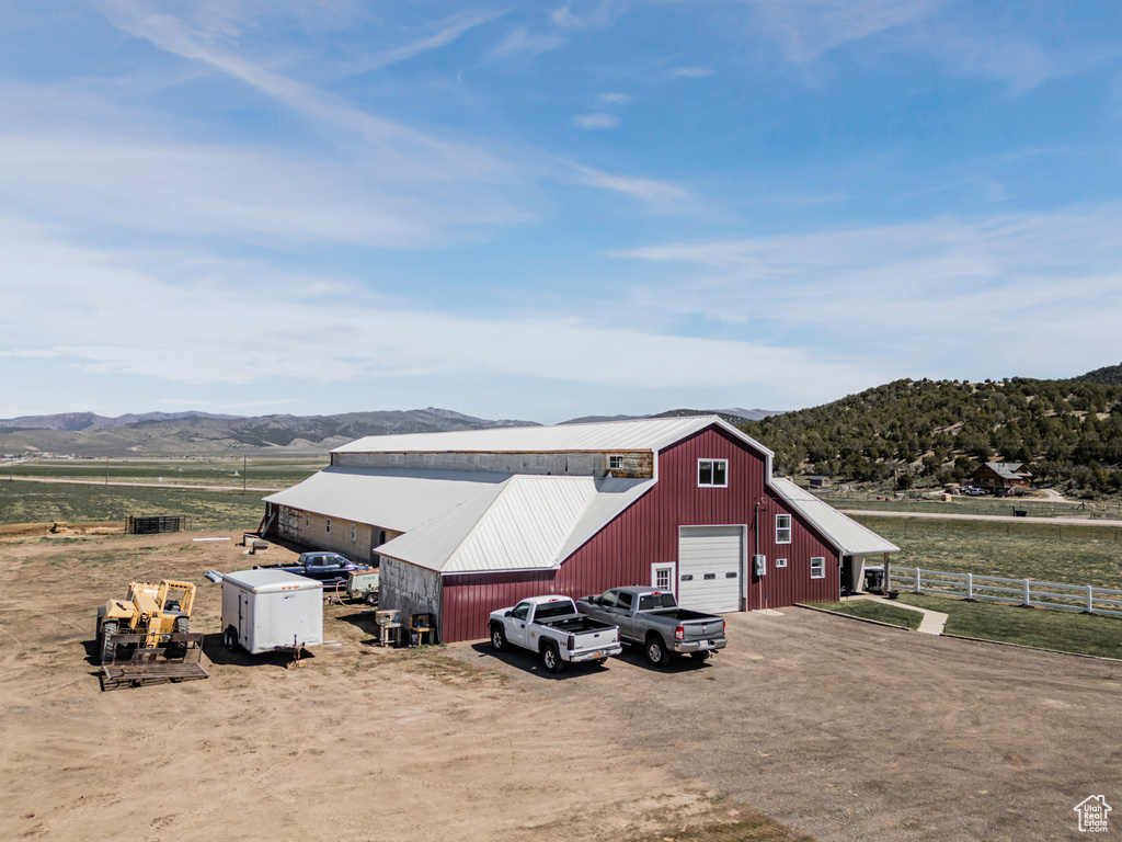 View of pole building featuring driveway, a mountain view, and a view of rural / pastoral area