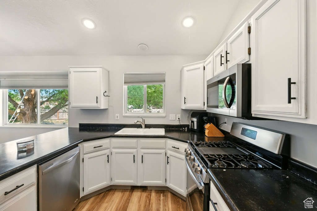 Kitchen featuring appliances with stainless steel finishes, white cabinetry, light wood finished floors, and recessed lighting