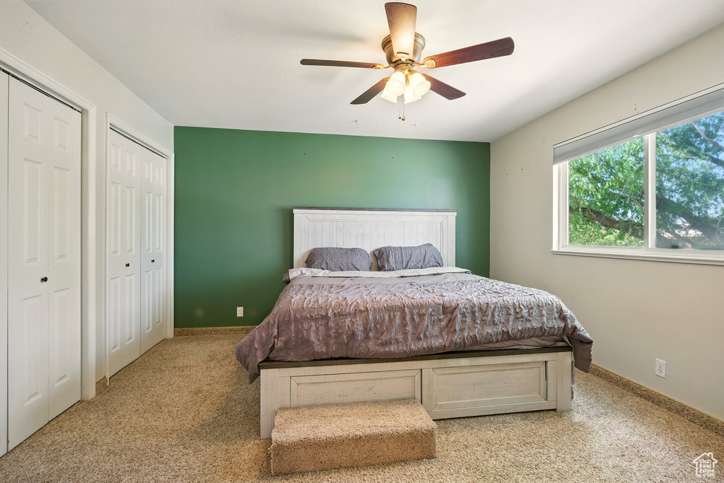 Carpeted bedroom featuring two closets and a ceiling fan