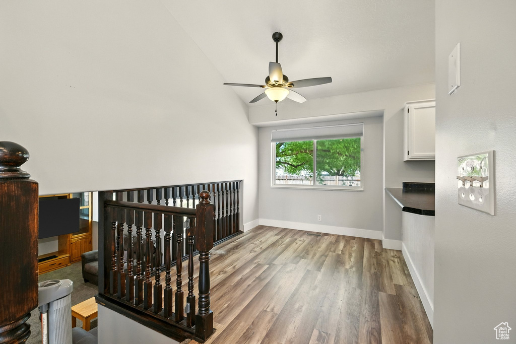 Interior space with a ceiling fan, wood finished floors, and lofted ceiling