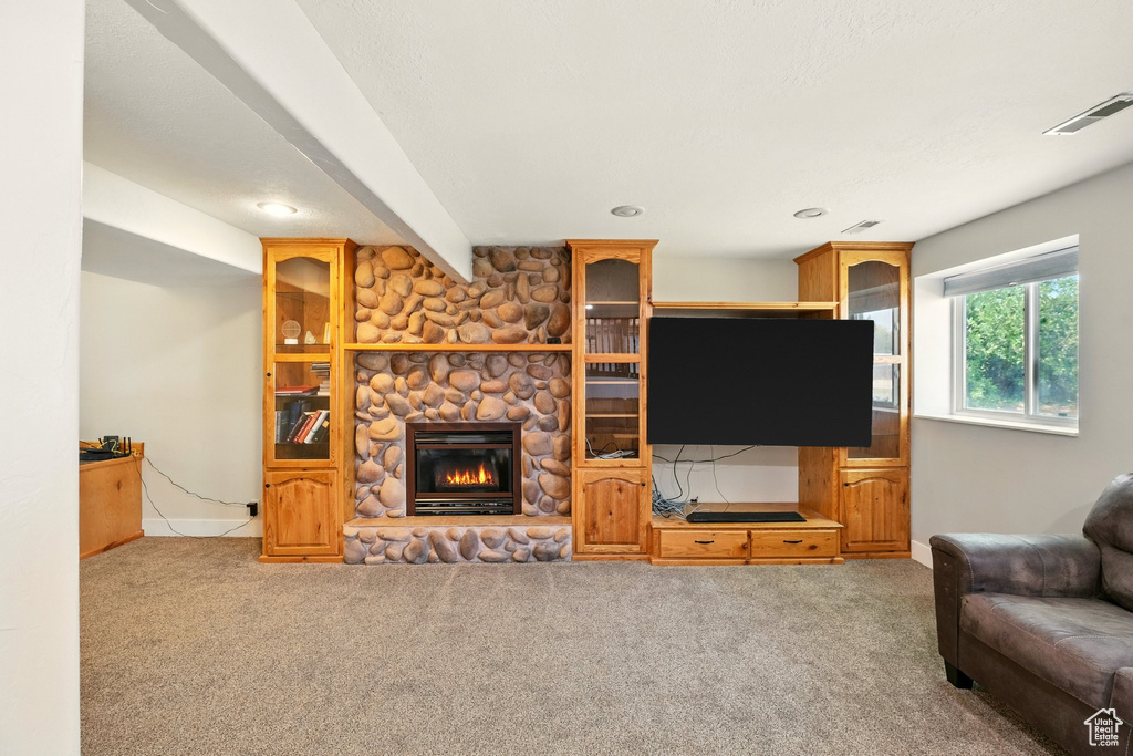 Living area with carpet floors, a stone fireplace, and recessed lighting