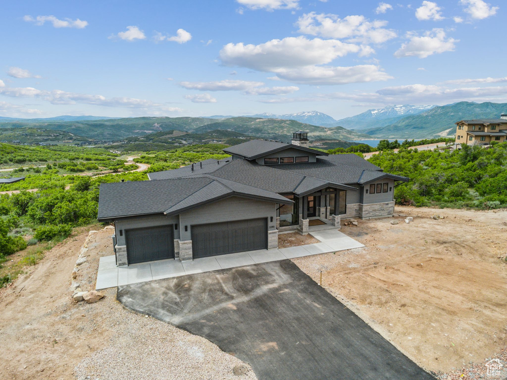 View of front of property with stone siding, a mountain view, an attached garage, and driveway