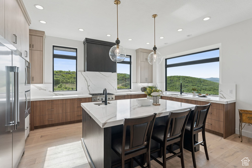 Kitchen featuring modern cabinets, high quality fridge, light wood-style floors, a kitchen island with sink, and recessed lighting