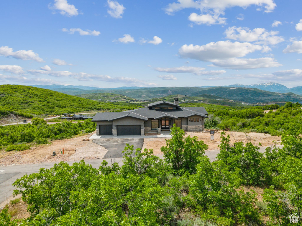 View of front of home with a garage, asphalt driveway, stone siding, and a mountain view